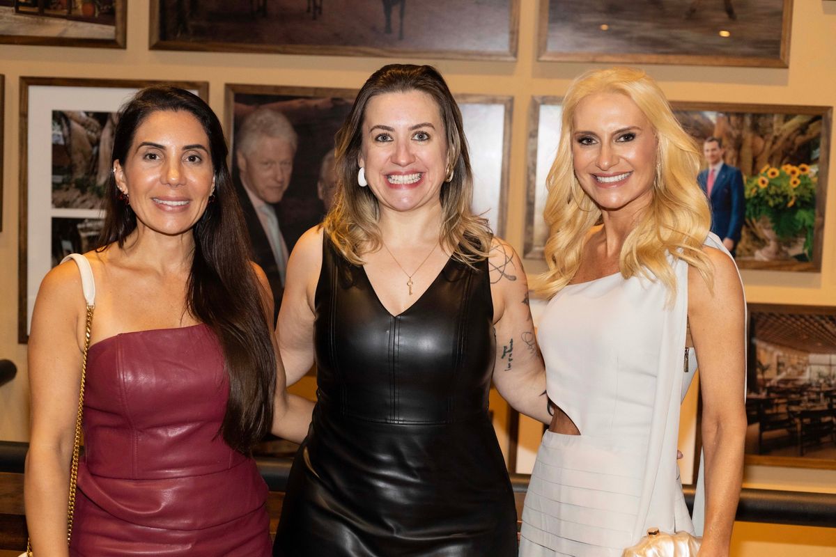Três mulheres sorrindo juntas durante o evento